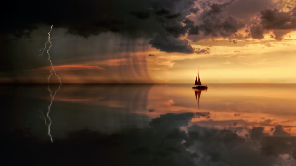 a rainstorm moving across the sea towards a sailboat at sunset.