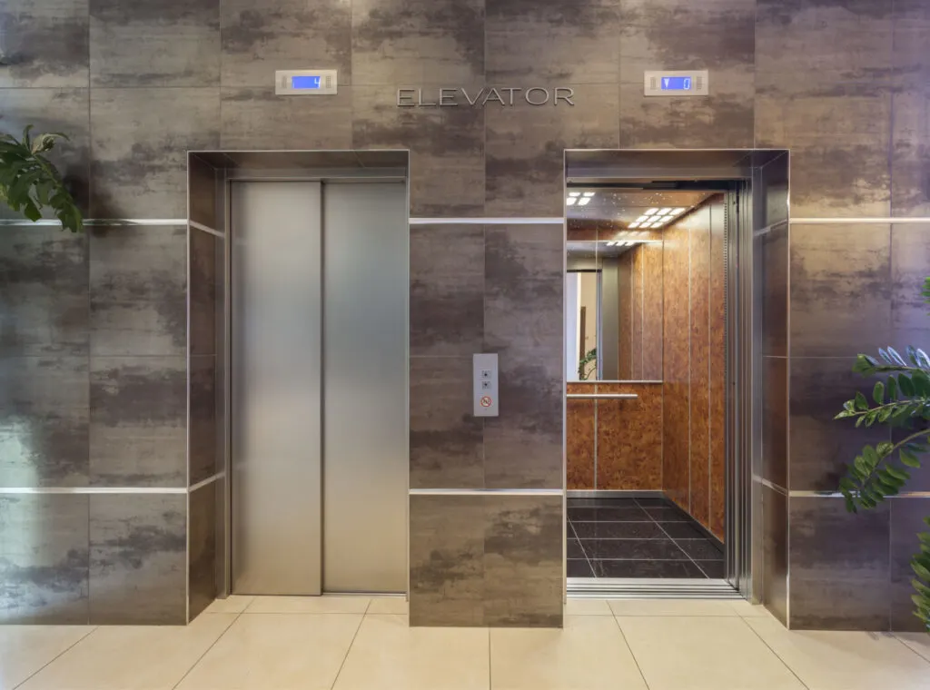 two elevators next to each other, one with doors close and one with doors open.