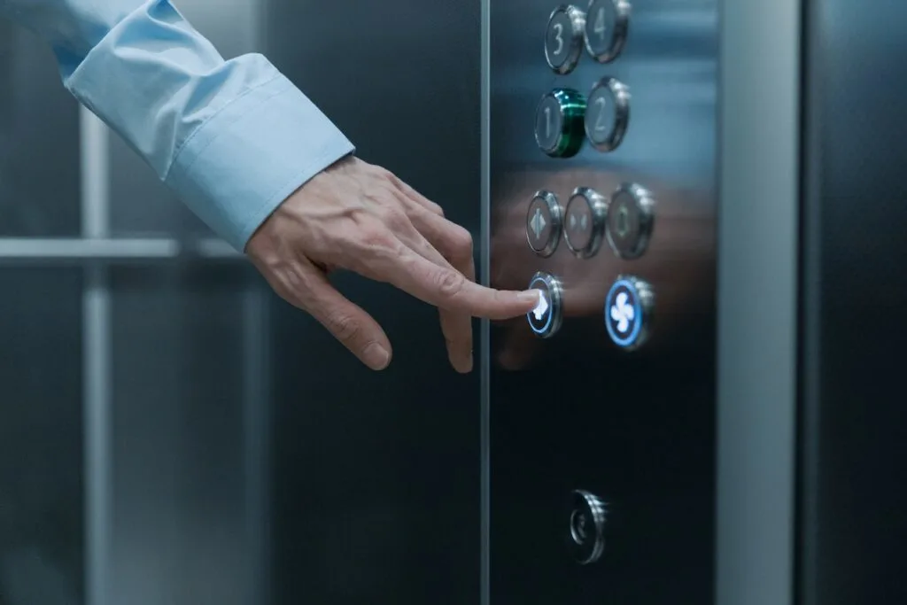 a man's fore finger pressing a button in an elevator.