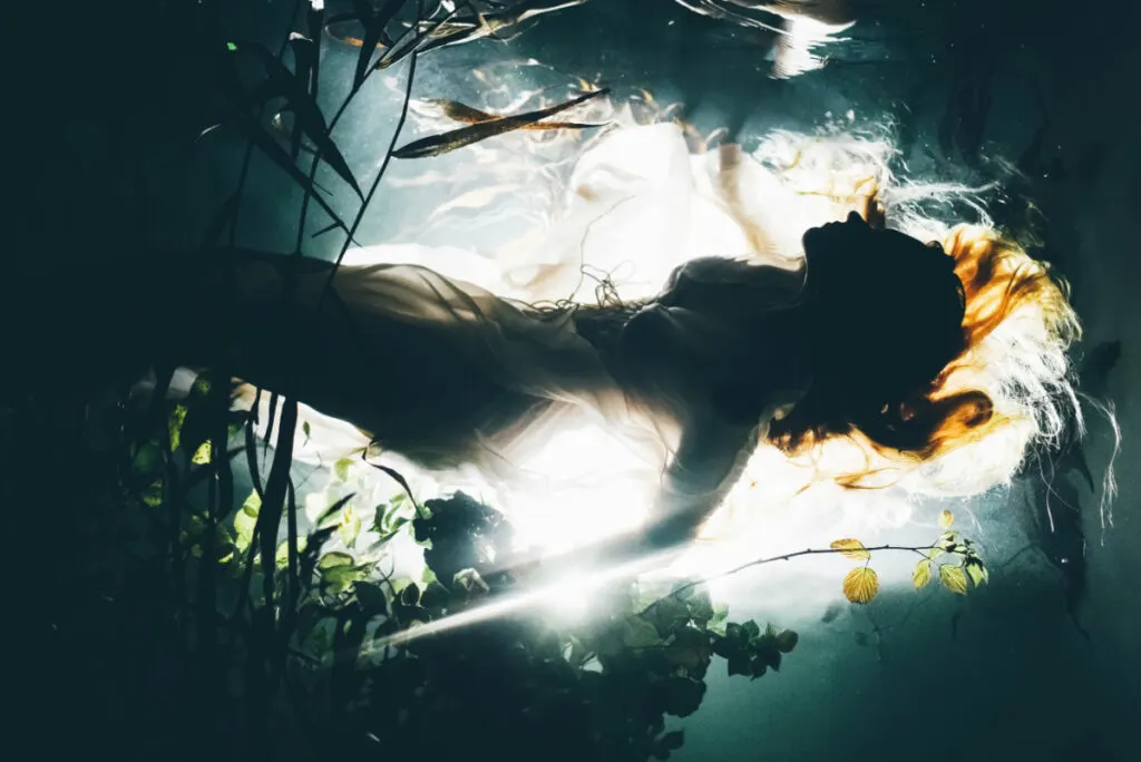 mysterious woman silhouetted under water.
