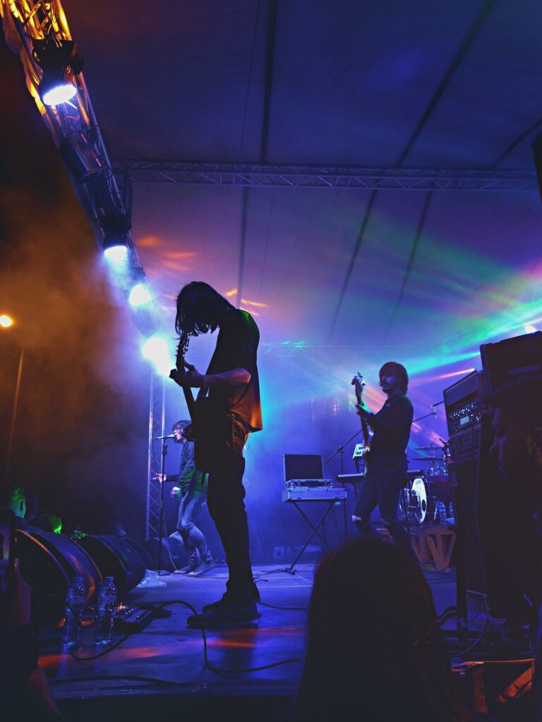 photo of a rock band with blue and green lights behind them.
