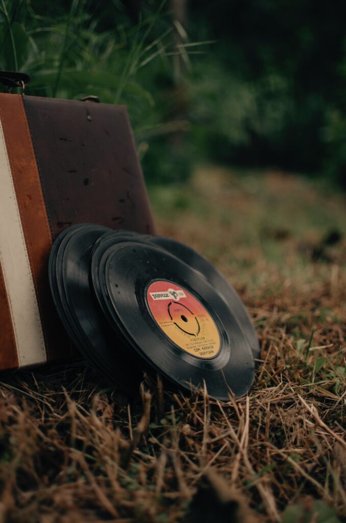 music records stacked against a record player in the grass.